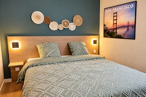 A bedroom with a bed, two bedside tables, a wall-mounted light, and a framed picture of the San Francisco Golden Gate Bridge. - San Francisco - Apartment in a complex with a pool (Neuf-Mesnil)