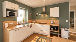A modern kitchen with white cabinetry, a microwave, a sink, and a coffee maker. - Malibu - Apartment in a complex with a pool (Neuf-Mesnil)