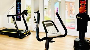 Un gimnàs modern amb dues cintes de córrer, una bicicleta estaciónia i un maniquí.