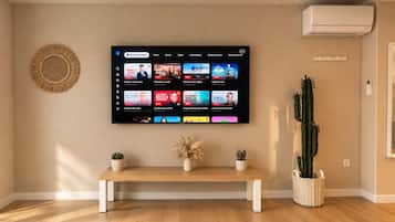 Un salon avec un téléviseur à écran plat fixé au mur, qui affiche l’interface d’un service de diffusion en continu.
