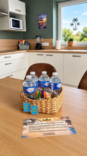 Una cocina con microondas, un cesto de agua embotellada y una tarjeta de bienvenida.