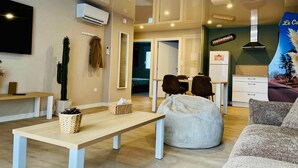 Una sala de estar moderna con un sofá, un sillón de pelota, una mesa y un televisor.