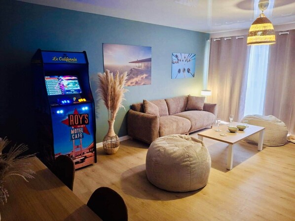 A hotel room with a sofa, a bean bag, a small table, a lamp, a wall-mounted TV, and a sign indicating a vacancy at Roy's Motel Cafe.