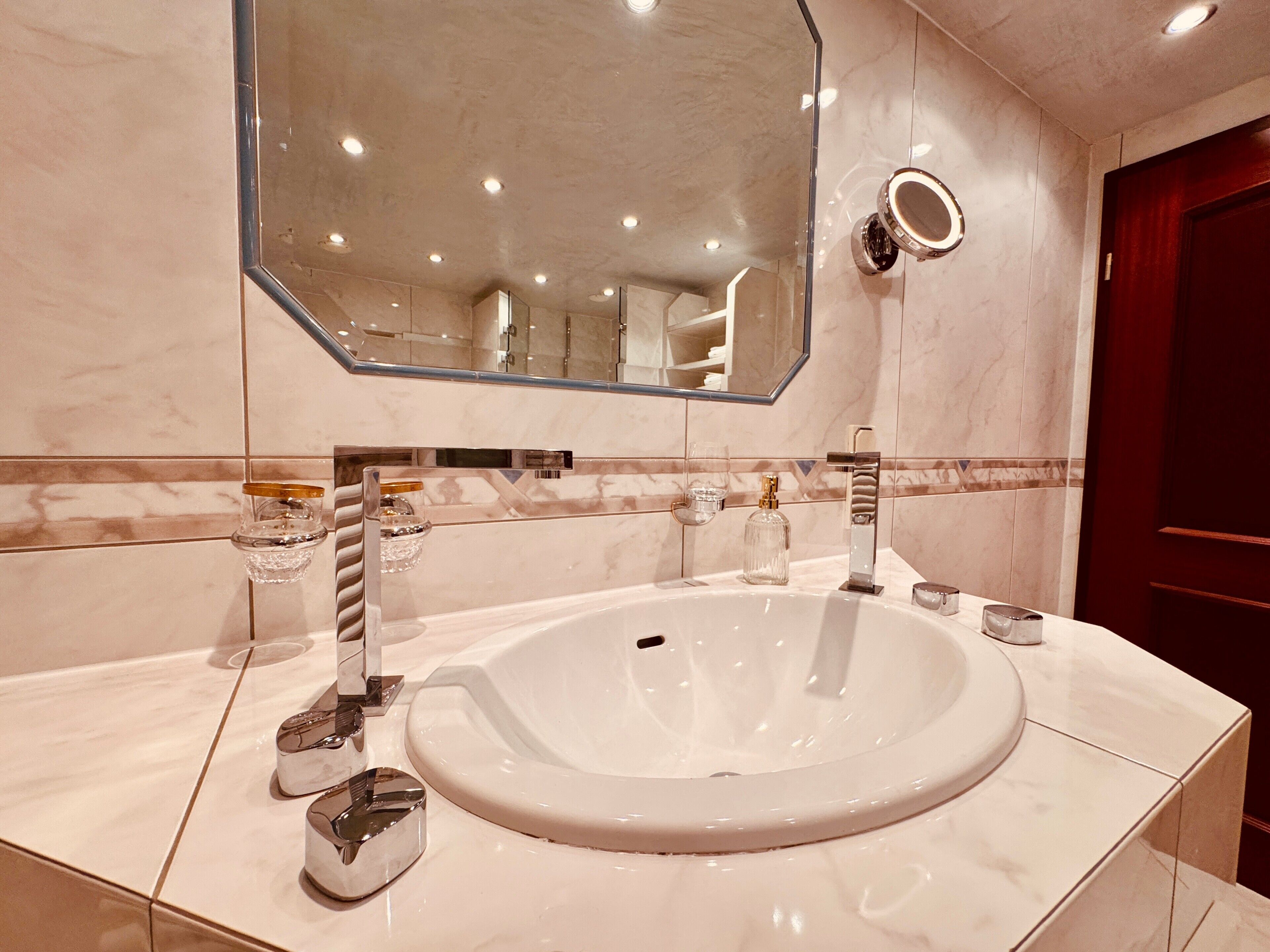 A bathroom with a large white sink, a mirror, and a red door.