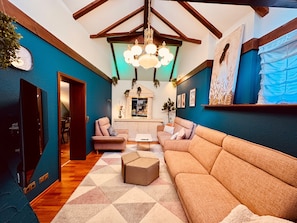 A living room with a sofa, armchairs, a coffee table, a chandelier, and a fireplace.