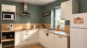 A kitchen with white cabinets, a microwave, a coffee maker, and a window with a view. - Santa Monica - Apartment in a complex with a pool (Neuf-Mesnil)