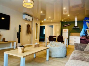 A modern living room with a sofa, a bean bag, a table, and a TV. - Laguna Beach - Suite in residence with swimming pool (Neuf-Mesnil)
