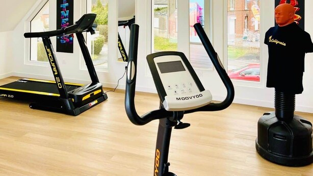 Un gimnàs modern amb dues cintes de córrer, una el·líptica i una bicicleta estaciónia.