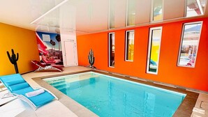 Una piscina interior amb gandules blaves, una decoració de cactus i un mural a la paret.