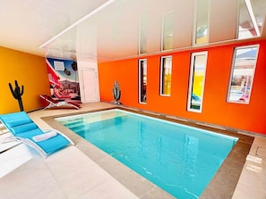 An indoor swimming pool with blue lounge chairs, a cactus decoration, and a mural on the wall. - Laguna Beach - Suite in residence with swimming pool (Neuf-Mesnil)