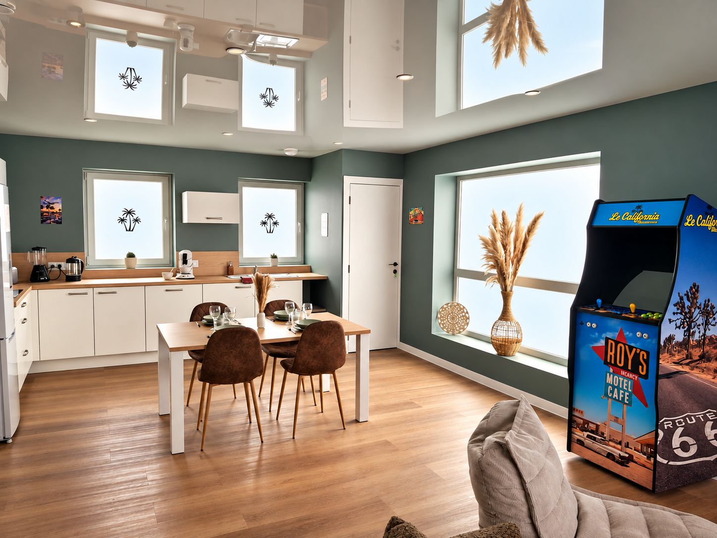 A modern kitchen with white cabinets, a dining area with brown chairs, and a large window with a view of the sky.