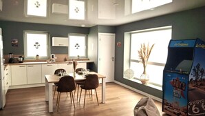 A modern kitchen with white cabinets, a dining table with chairs, and a large window with a view of the desert. - Palm Springs - Family suite with pool (Neuf-Mesnil)