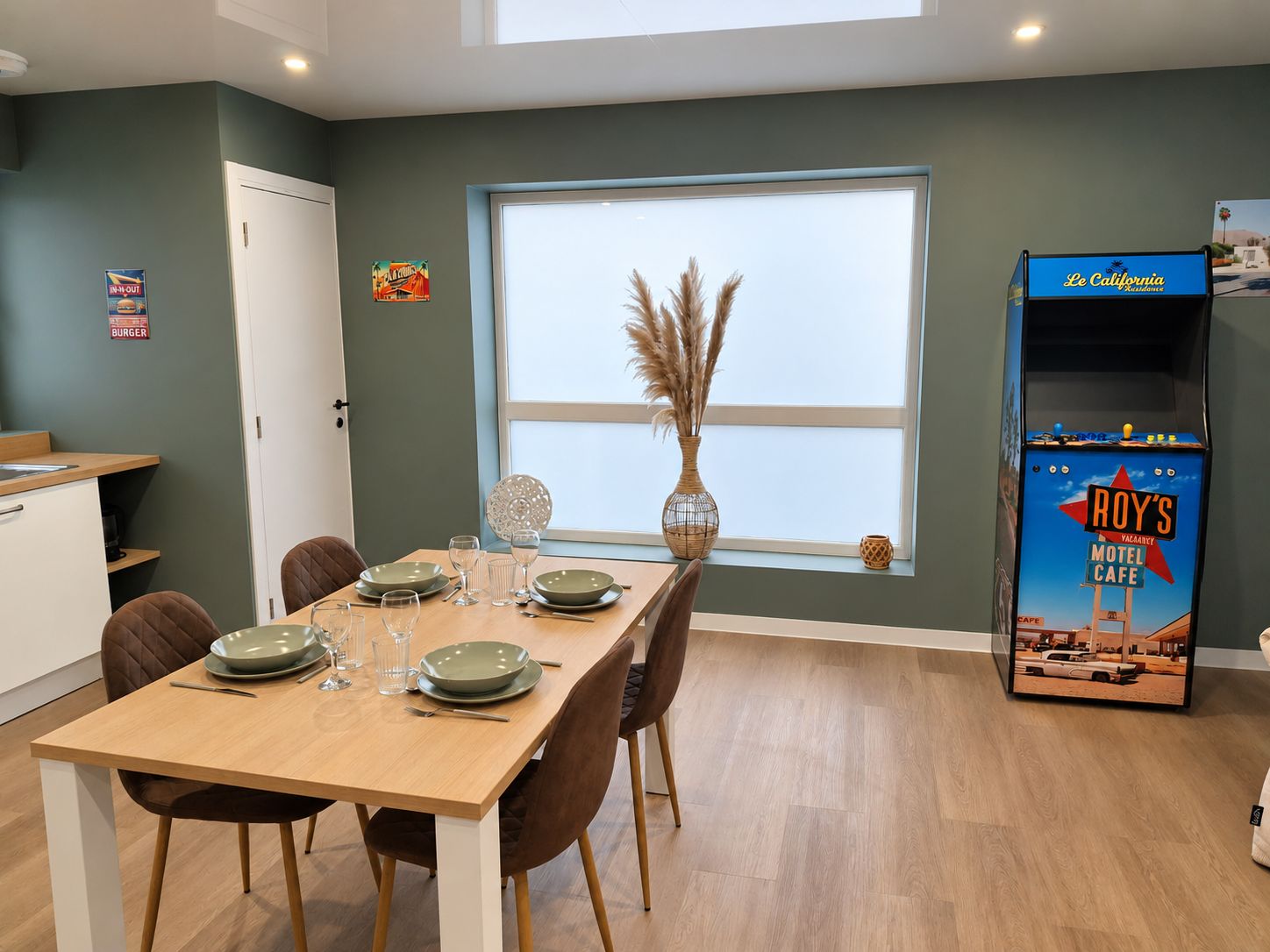 A dining area with a table set for four, a window with a view, and a Roy's Motel Cafe sign.