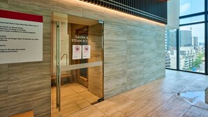 Un interno moderno con sauna e indicazione per il bagno turco, un pavimento in legno e vista sulla città attraverso ampie finestre.