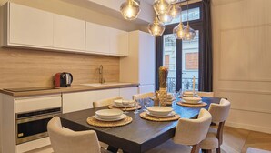 Una cucina moderna con elettrodomestici integrati, un'area pranzo con un tavolo in legno scuro e illuminazione a sospensione.
