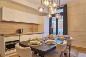 Eine moderne Küche mit Einbaugeräten, ein Essbereich mit einem dunklen Holztisch und Pendelleuchten.
