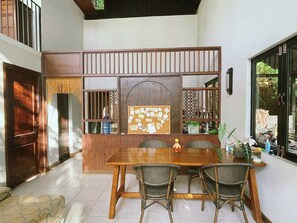 Un comedor con una mesa y sillas de madera, un tablón de anuncios y vistas por una ventana.