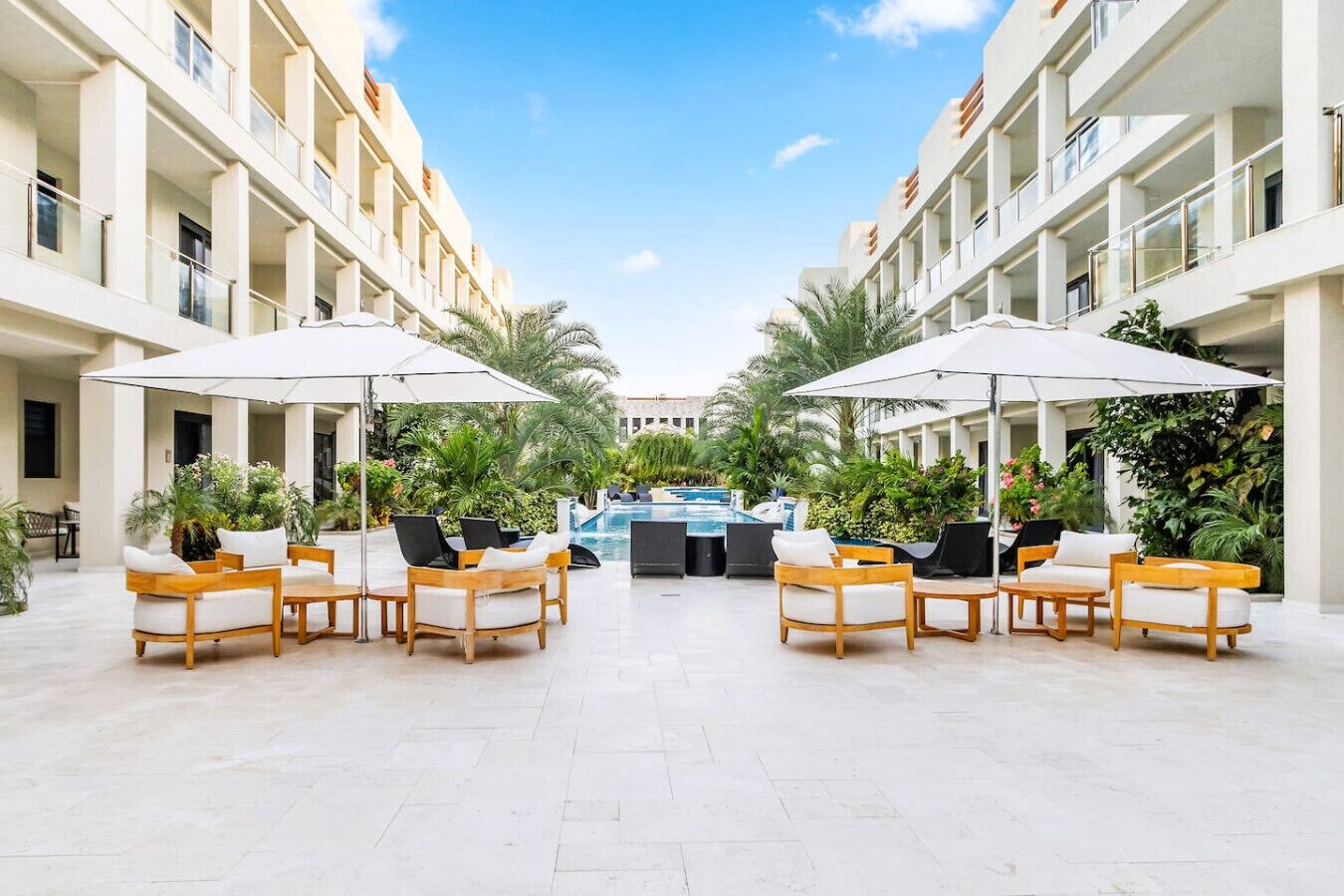 A hotel courtyard with outdoor seating, a pool, and lush greenery.