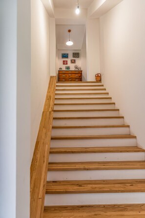 A staircase with wooden steps and a wooden handrail, leading to a room with a dresser and wall art. - Wolves Room - Casa Silva (Lorica)