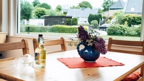 A dining table with a vase of flowers, a bottle, and a placemat.