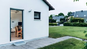 A modern house with a sliding glass door leading to a dining area with a table and chairs.