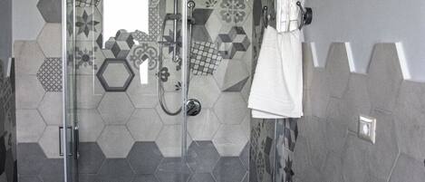 Ducha con puerta de vidrio, toallero y unidad de aire acondicionado de pared.
