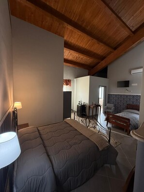 A bedroom with a bed, a nightstand, a lamp, a TV, and a wooden ceiling. - B & B Foresta Vini (Telese)