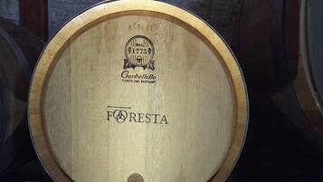 A wooden barrel with 'FORESTA' and 'NIR' labels, placed on a stand in a dimly lit room with stone walls.