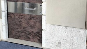 Eine Tür mit einem Metallgriff, einer Metallplatte mit der Aufschrift 'B & B by FORESTA', einer Wandleuchte und einer Fußmatte.