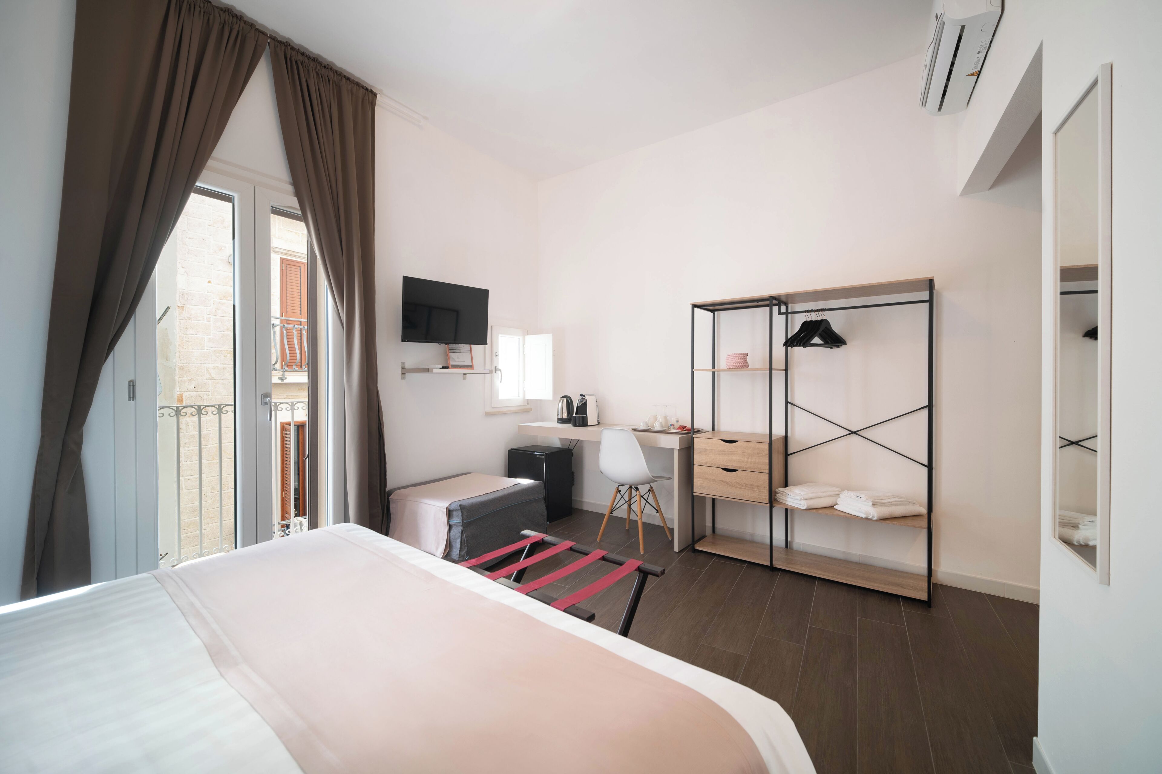 A hotel room with a bed, a desk, a chair, a wardrobe, and a television.