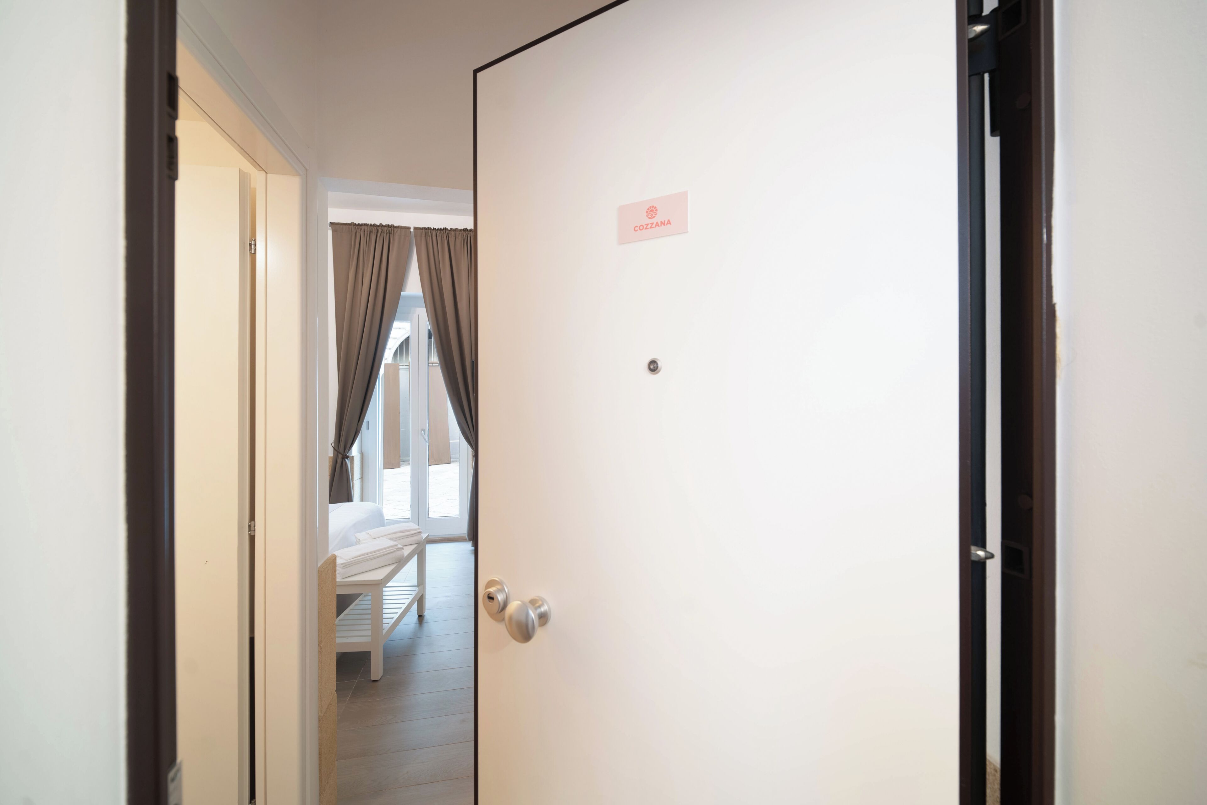 Habitación de hotel con cama, una puerta con placa de identificación y vistas al exterior.