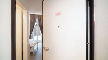 Habitación de hotel con cama, una puerta con placa de identificación y vistas al exterior.