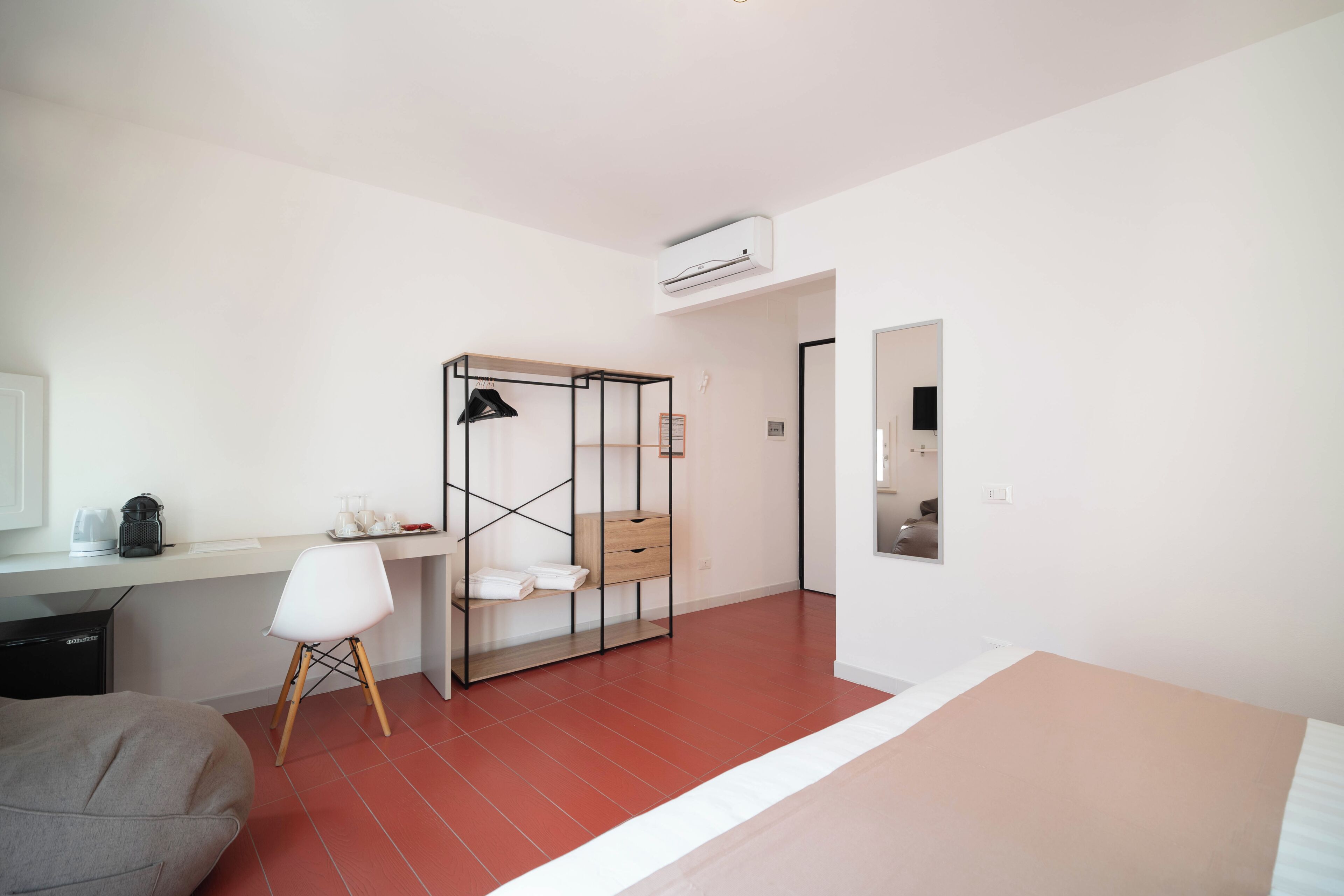 A modern hotel room with a desk, chair, wardrobe, and a bed.