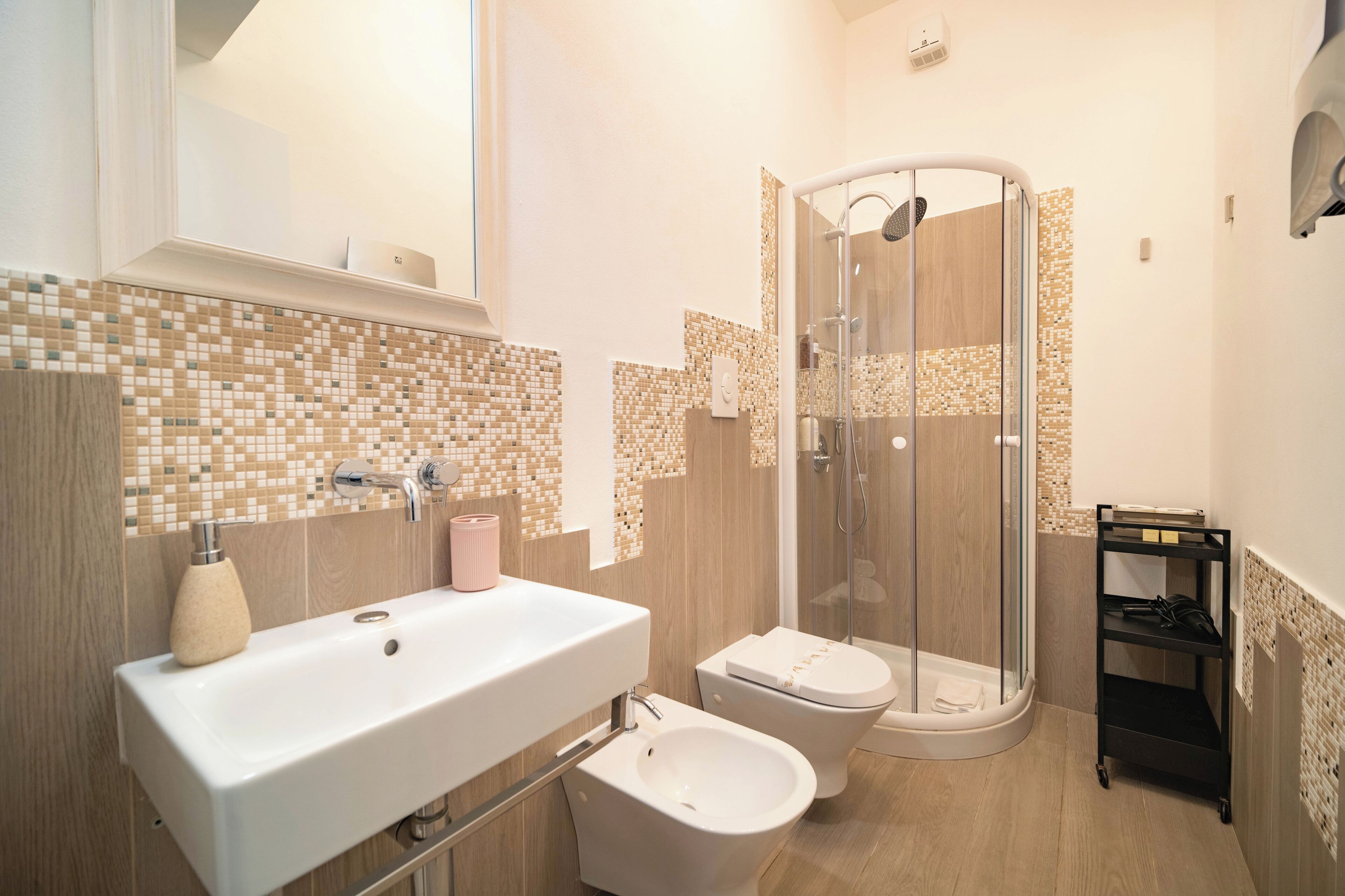 A bathroom with a sink, bidet, and glass-enclosed shower.