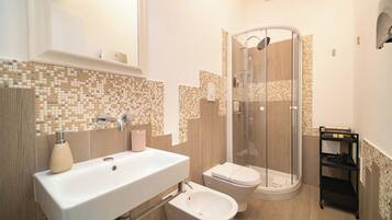 A bathroom with a sink, bidet, and glass-enclosed shower.