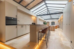 Une cuisine moderne dotée d’un îlot central, de tabourets de bar et d’une verrière.