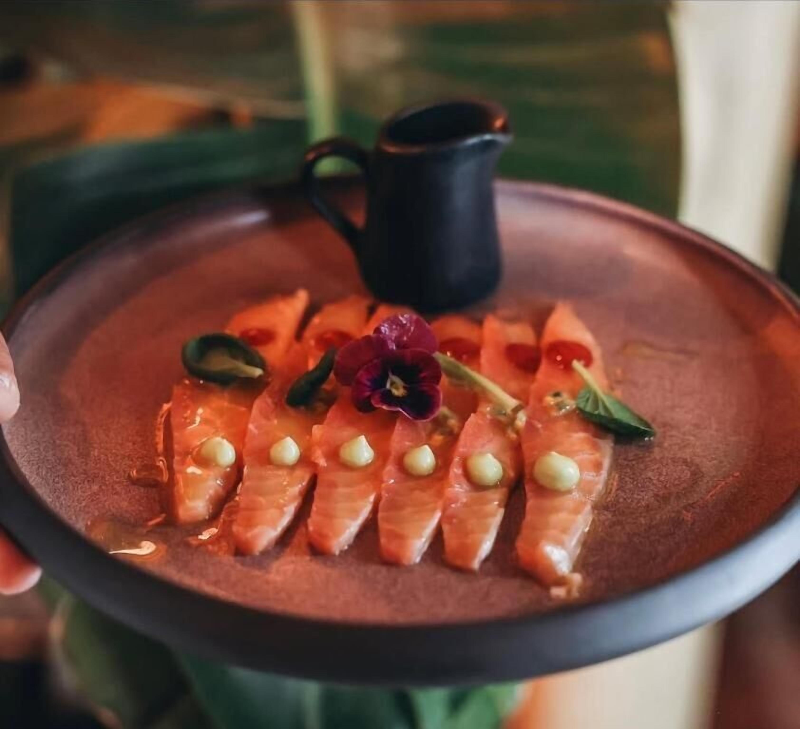 Une assiette de sashimi de saumon et un petit pichet.
