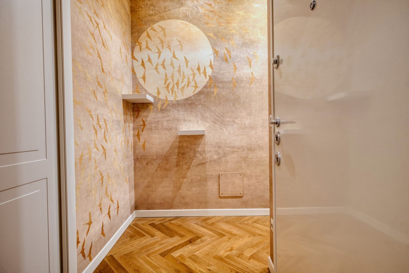 Un baño con piso de madera, una pared con diseño circular y una puerta.
