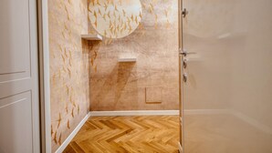 Une salle de bain avec un plancher en bois, un mur orné d’un motif circulaire et une porte.