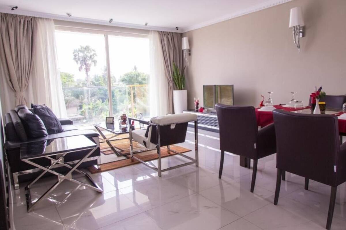Habitación de hotel con comedor, sofá, mesa de centro y vistas al exterior.