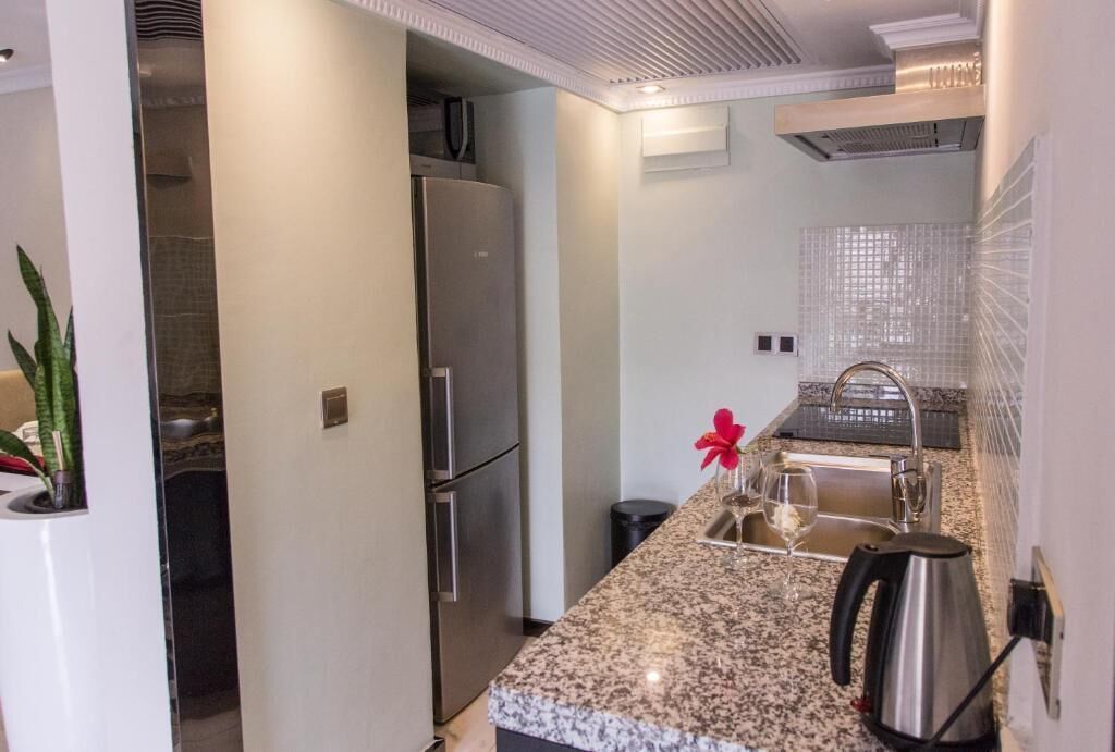 Una cocina moderna con encimera de granito, electrodomésticos de acero inoxidable y un lavamanos pequeño.