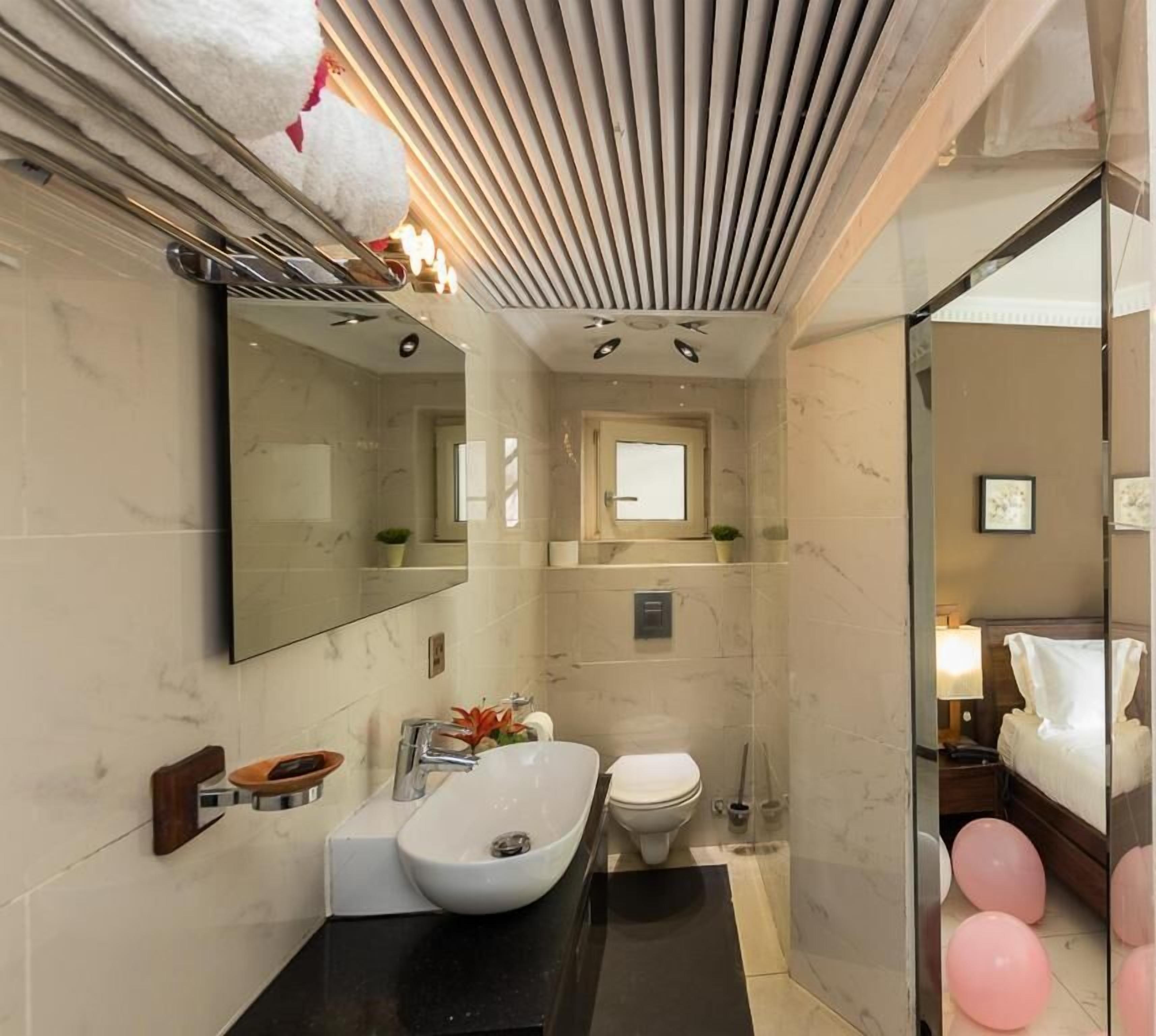 Ein kleines Hotelbad mit Waschbecken, Toilette und Spiegel.