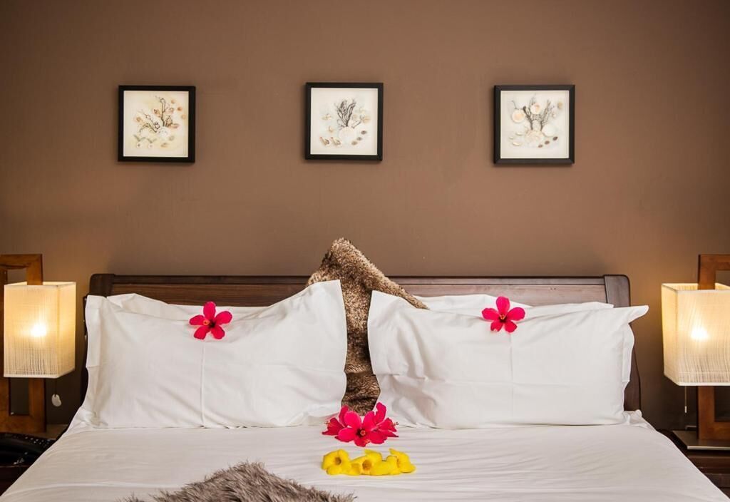 Una habitación de hotel con cama, almohadas y una obra de arte colgada en la pared.