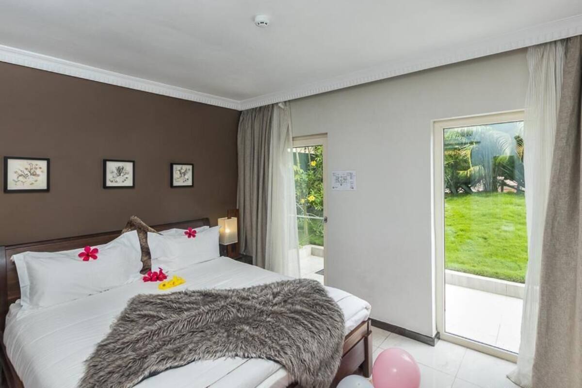 Habitación de hotel con cama, vista a un jardín y puerta que da al exterior.