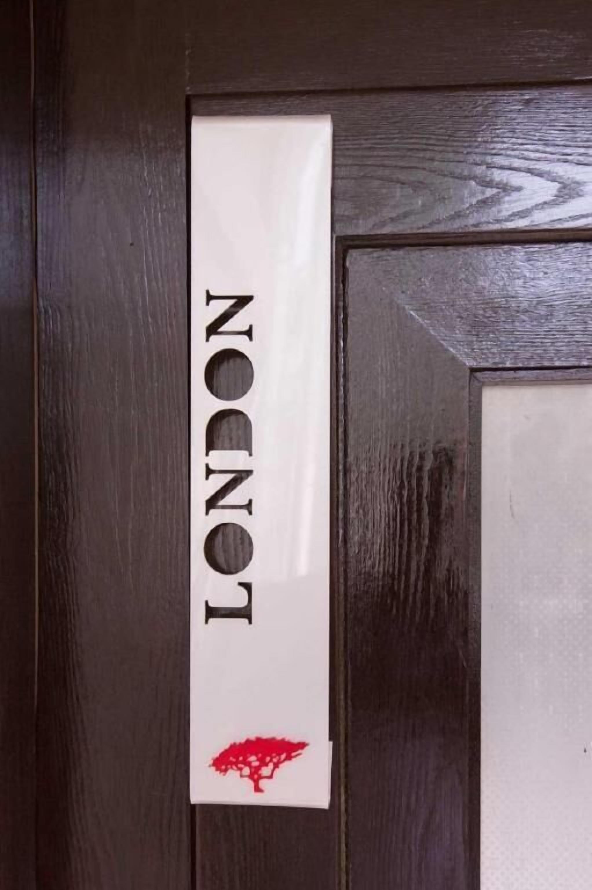 Eine Tür mit einem Schild, auf dem 'LONDON' steht, und einem roten Baum-Logo.