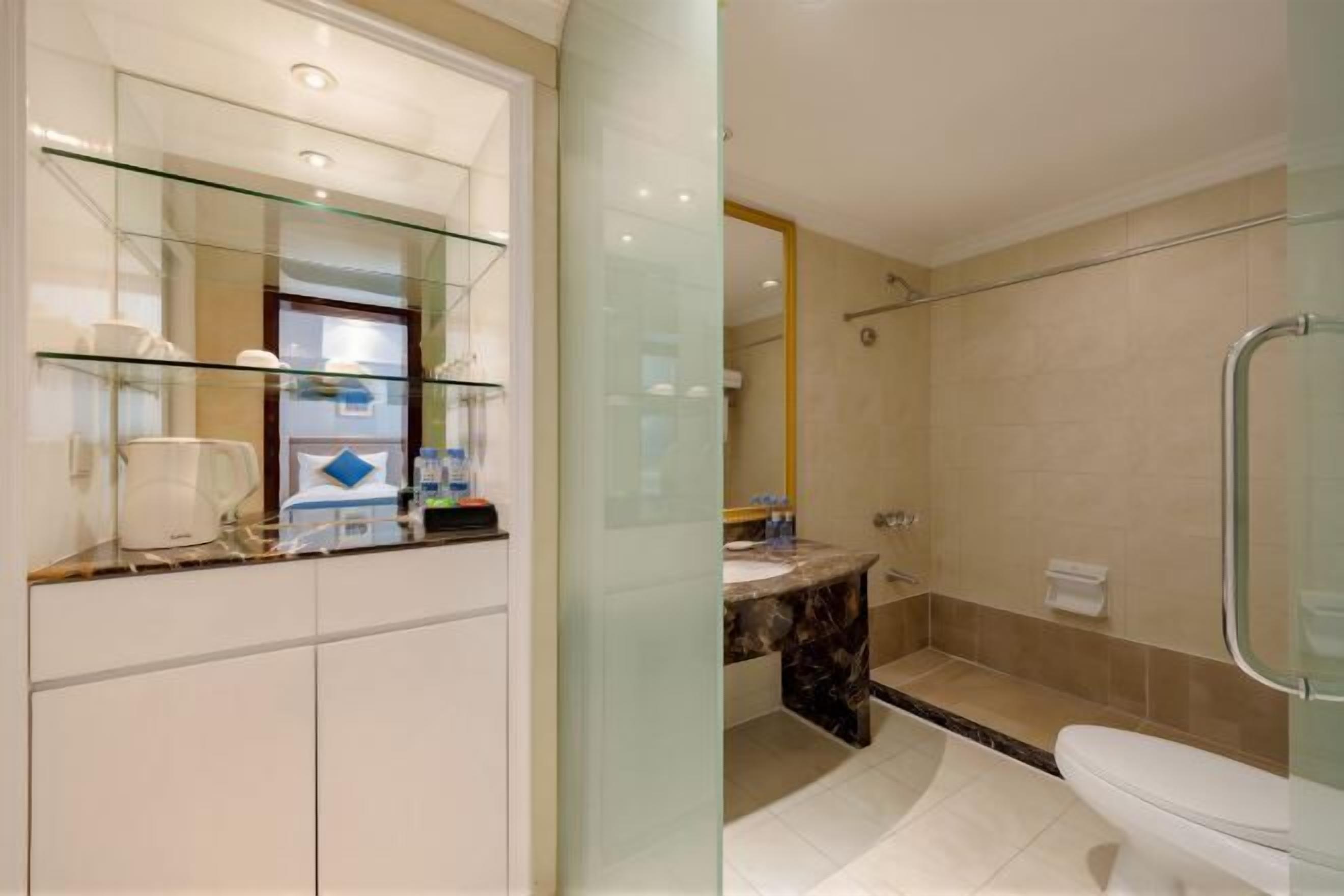 A modern bathroom with a glass shower enclosure, a marble sink, and a white toilet.