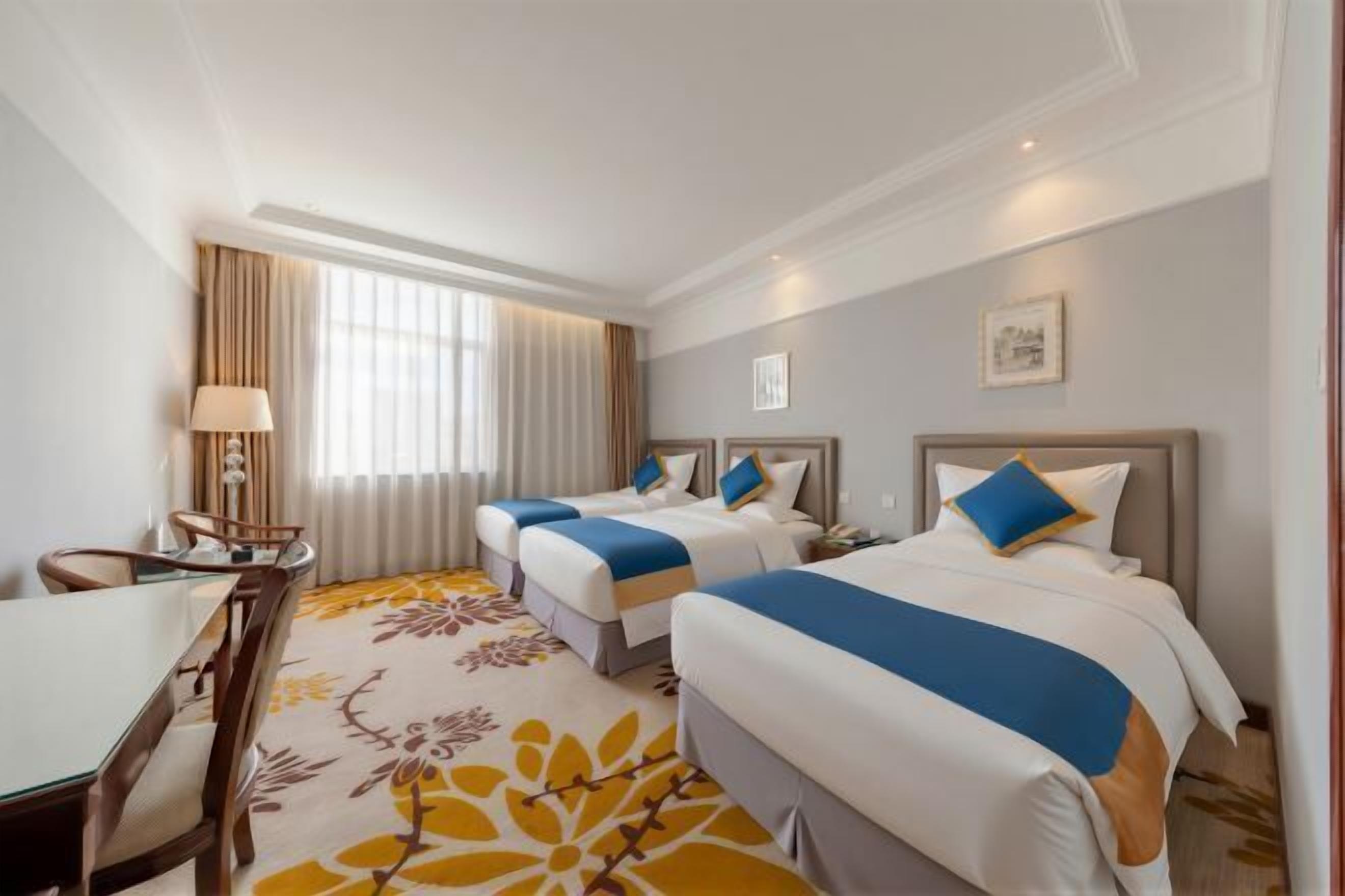 A hotel room with two beds, a desk, and a chair.