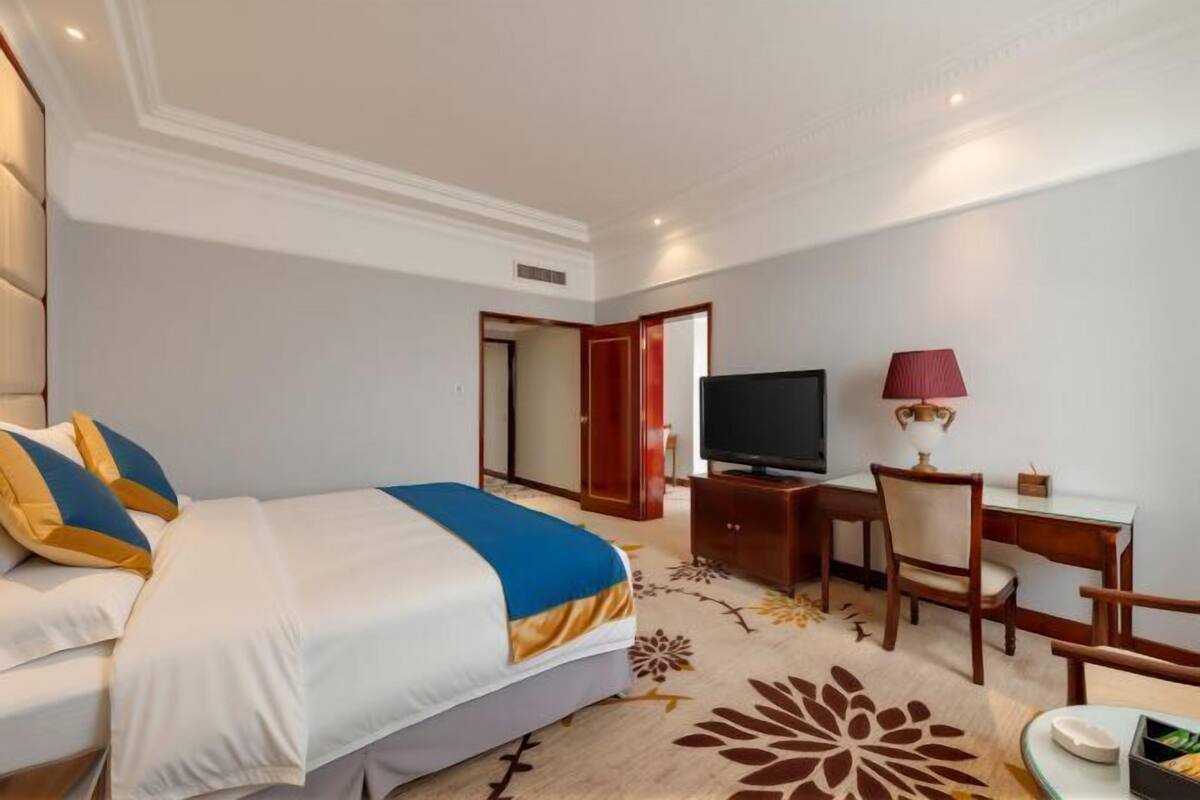 A hotel room with a bed, a desk, a television, and a chair.