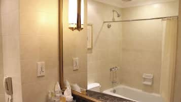 A bathroom with a bathtub, shower, and a large mirror.