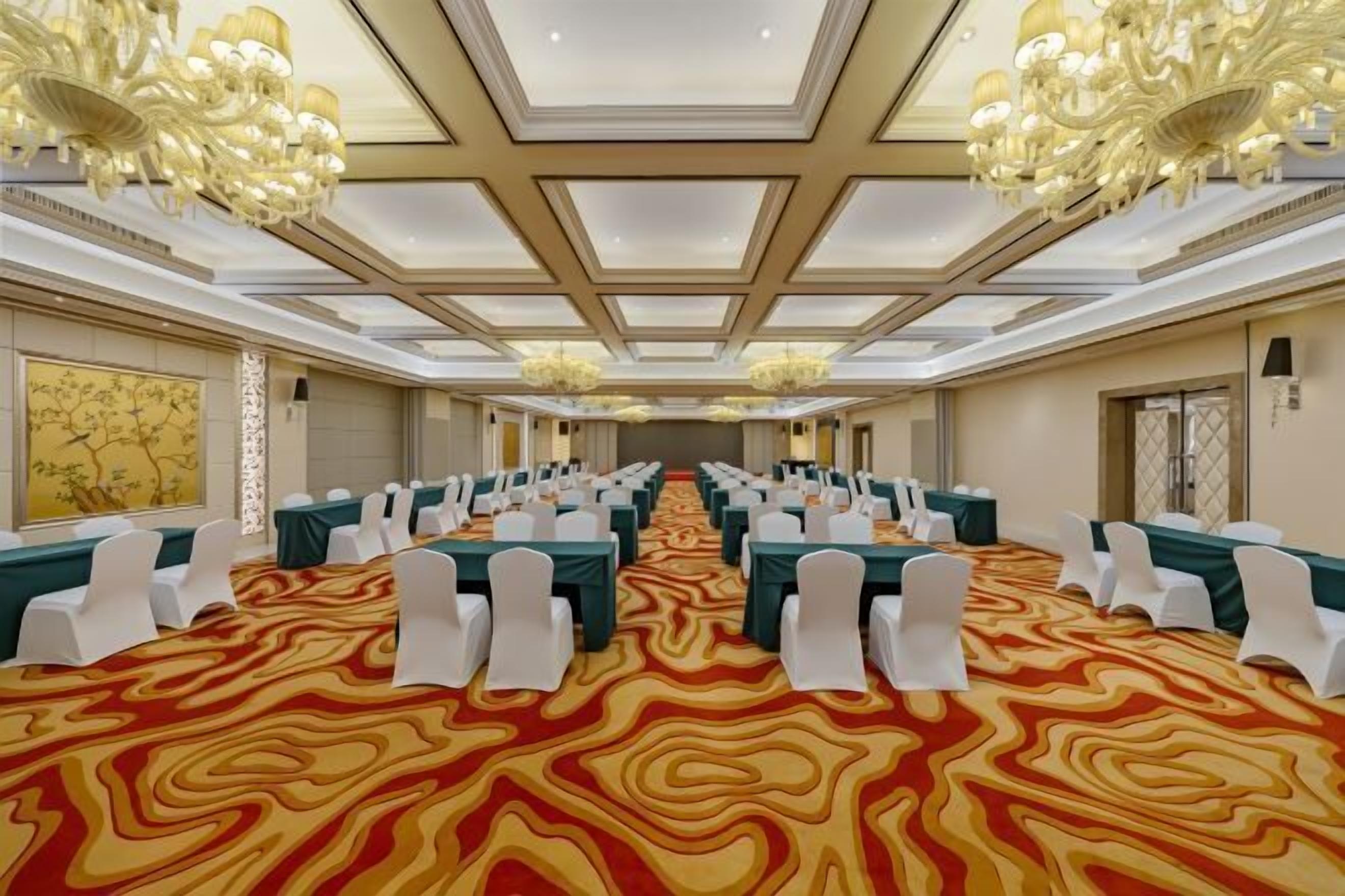 A conference room with a patterned carpet, white chairs, and tables arranged for a meeting.